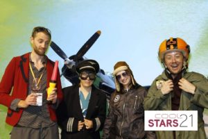 the cool stars group gather in various aero-themed gear in front of a large aeroplane.